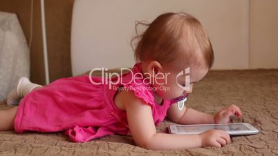 Small kid lying on sofa and playing with tablet