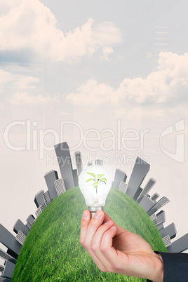 Composite image of hand holding environmental light bulb