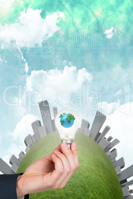 Composite image of hand holding environmental light bulb