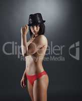 Glamorous tanned woman posing topless in hat