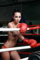 Half-naked brunette posing in red boxing gloves