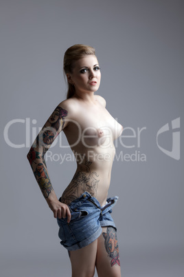 Half-naked tattooed girl takes off her shorts