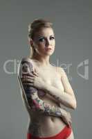 Studio shot of cute nude woman with tattoos