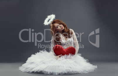 Feminine Cupid. Girl in angel costume with heart