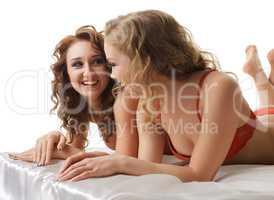 Beautiful girlfriends laugh while lying in bed