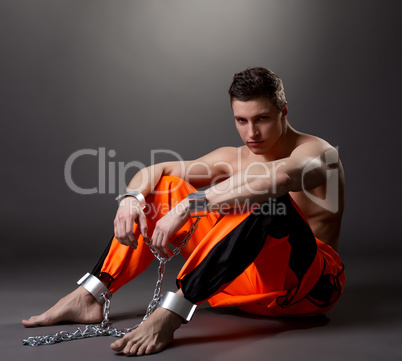 Handsome male model posing as prisoner in studio