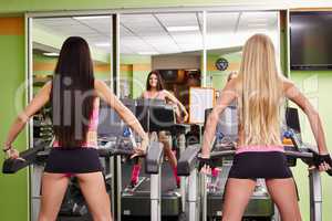 Rear view of sporty girls exercising on treadmills