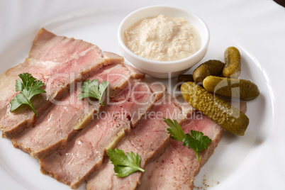 Close-up of smoked meat with sauce and pickles