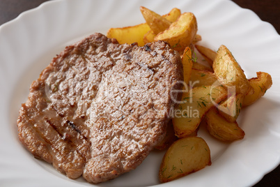 Delicious pork chop and potato wedges, close-up