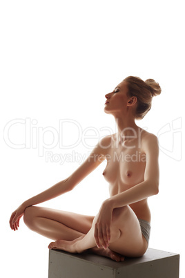 Sensual woman posing topless while sitting on cube