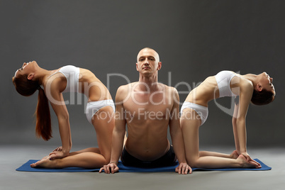 Relaxed people practicing yoga threesome in studio