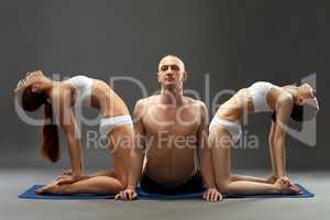 Relaxed people practicing yoga threesome in studio