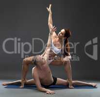 Attractive yoga couple exercising in studio