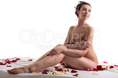 Mehandi. Brunette posing nude in bed with petals