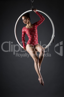 Cute artistic gymnast exercising with hanging hoop