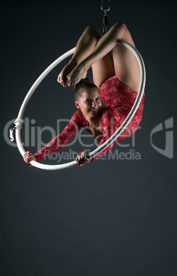 Happy female acrobat performs with hanging hoop