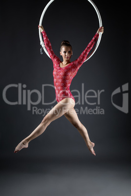 Lovely gymnast posing while performs with hoop