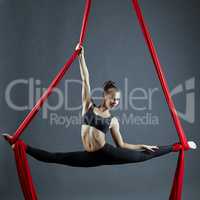 Cute dancer doing gymnastic split on aerial silks