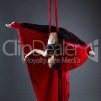 Graceful dancer on aerial silks posing upside down