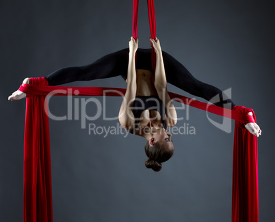 Sexy female acrobat performs hanging upside down