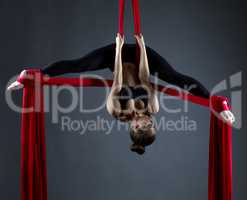 Sexy female acrobat performs hanging upside down