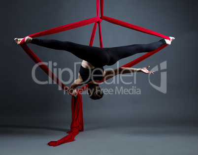 Studio shot of acrobat performs on hanging ribbons