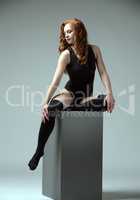Attractive girl sitting on cube. Fitness concept