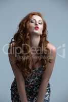Red-haired fashion model blowing kiss at camera
