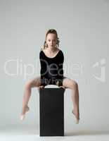 Beautiful young gymnast training on cube