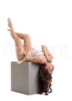 Alluring woman lying on cube. Studio photo