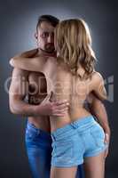 Handsome bodybuilder hugging slim topless girl