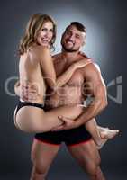 Happy topless woman in arms of handsome strong man