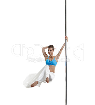 Pretty female dancer spinning on pole in studio