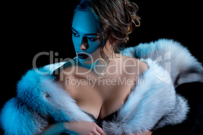 Luxury woman with deep neckline posing in fur