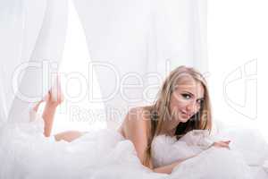 Nice blonde posing at camera while lying in bed