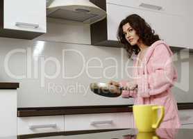 Kitchen. Pretty brunette posing with frying pan