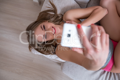 Top view of girl doing selfie while lying on sofa