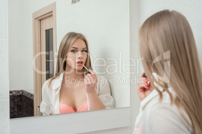 Reflection in mirror of sexy girl paints her lips