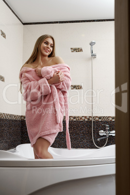 Bathroom. Image of smiling model in pink bathrobe