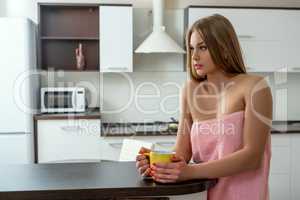 Sexy woman with cup posing in kitchen after shower