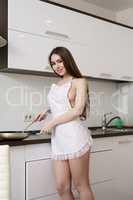Charming brunette in sexy apron cooking on kitchen