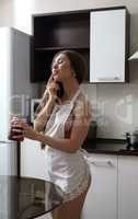 Seductive housewife tasting jam in kitchen