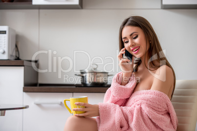 Woman talking on cellular while having breakfast