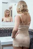 Rear view of hot blonde looks at herself in mirror