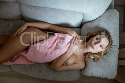 Top view of languid nude blonde lying on sofa