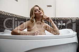 Sexy blonde posing languidly while taking bath