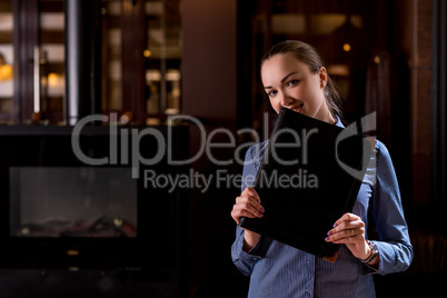 Smiling waitress hiding her face behind menu