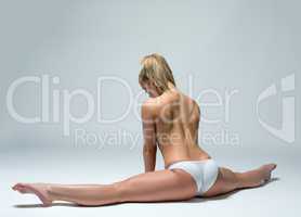 Rear view of topless woman doing gymnastic split