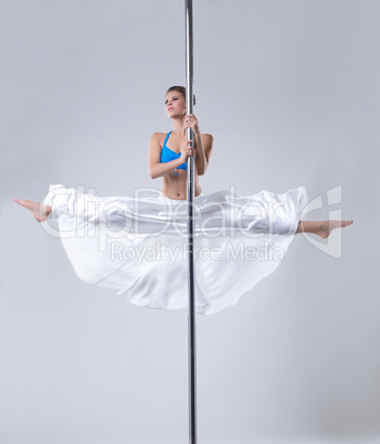 Cute girl easily performs gymnastic split on pole