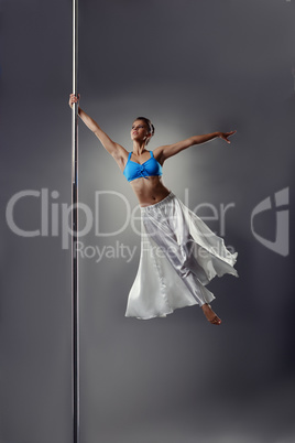 Pole dance. Beautiful girl spinning around pylon